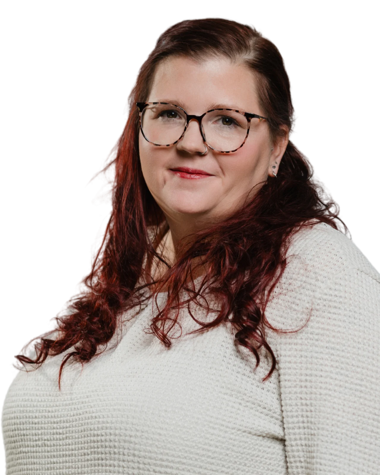 Porträt einer Frau mit langen, welligen, dunkelroten Haaren und einer Brille mit dunklem Rahmen. Sie trägt einen cremefarbenen Strickpullover und hat ein freundliches Lächeln.